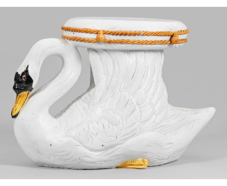 Keramik, farbig glasiert. Vollplastisch gearbeitet. Hockender Schwan, seine Flügel in die Höhe gestreckt, darauf ein stilisie