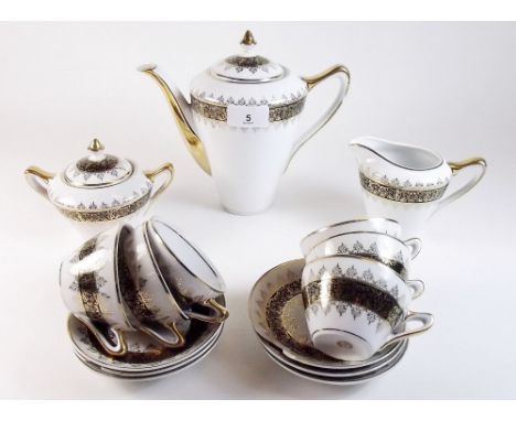 A continental coffee service comprising six cups and saucers, coffee pot, milk and sugar with gilt and black decoration