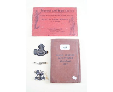 A Field Service Pocket Book, Trumpet and Bugle Sounds' music book, two military cap badges and a fabric bugle badge