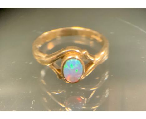 A black opal cabochon ring, approx 0.25ct, with strong green blue and violet colour play, open shouldered 9ct gold shank, siz