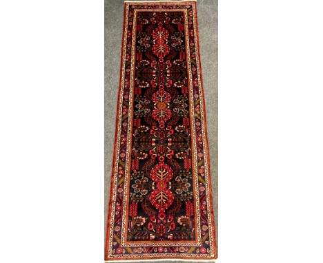 A North West Persian Rudbar runner carpet, hand-knotted with a central field of three repeating floral medallions, and stylis