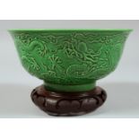 A CHINESE GREEN GLAZED PORCELAIN DRAGON BOWL with hardwood stand, the exterior with carved