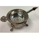 A heavy modern silver tea strainer on stand.