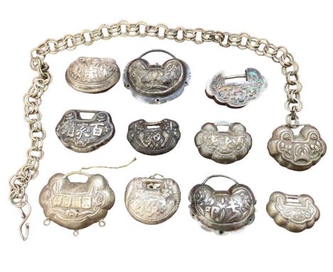 Collection of eleven Chinese white metal padlock style pendants with floral scroll and character mark decoration, one with ch