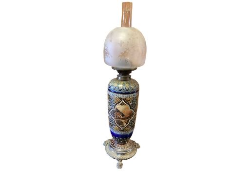 Doulton Lambeth stoneware oil lamp with glass shade and chimney, raised on brass feet