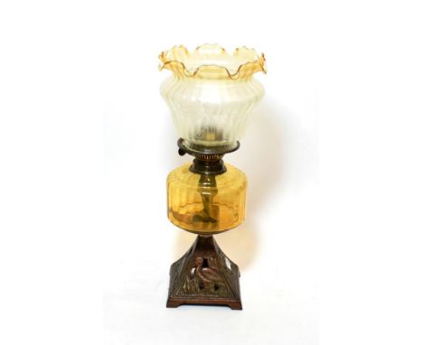 ^ A late Victorian oil lamp with yellow tinted glass reservoir, the metal base in the form of pelicans, 48cm high
