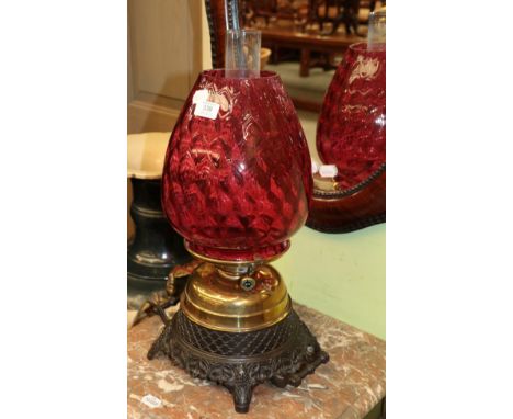 A brass and patinated metal oil lamp with artichoke form ruby glass shade 