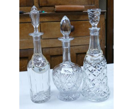 Three crystal decanters: two with ceramic labels 