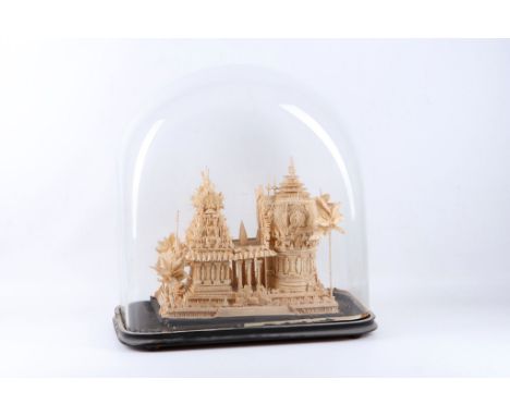 A balsa wood model of an Asian temple under glass dome.