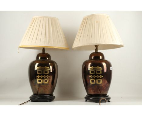 A pair of porcelain burgundy lustre glazed lamp bases, both having Oriental gilded motto, with shades, 60cm high.