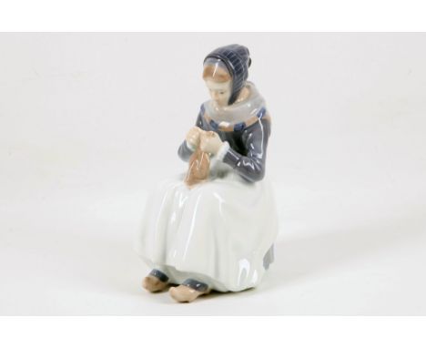 A Royal Copenhagen porcelain model of a girl wearing regional costume sitting on a stool, signed on the back, Beuter 1911, 23