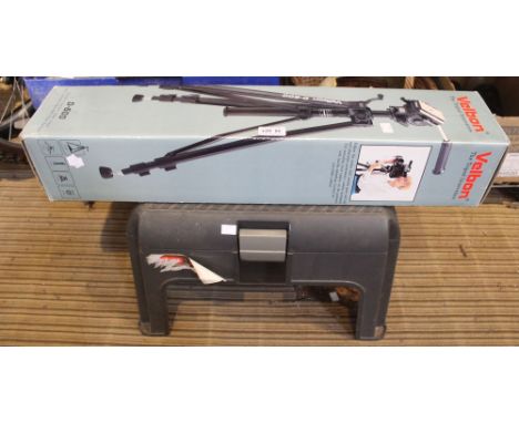 A plastic step carry box containing shoe shining equipment with a boxed tripod