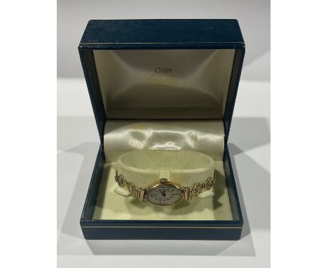 A lady's 9ct gold watch, the oval engine turned dial with Arabic numerals, the case marked 375, gold coloured metal fancy lin