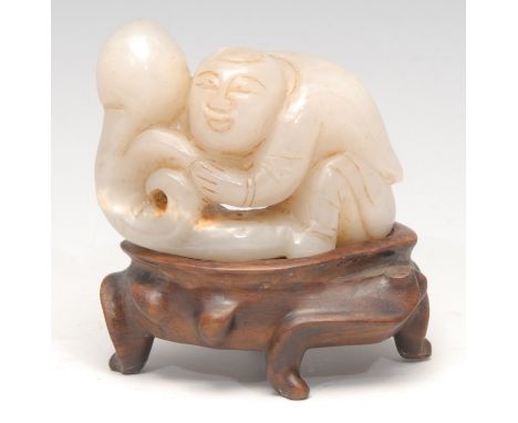 A Chinese jade carving, of a figure holding a peach, 6.5cm wide, hardwood stand 