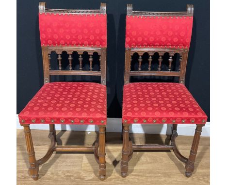 A pair of Arts and Crafts oak side chairs, the spindle centred ladder backs applied with fabric, brass rosette rivets, shaped