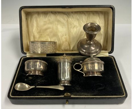 A silver three piece cruet set; a silver candlestick; a silver bangle 