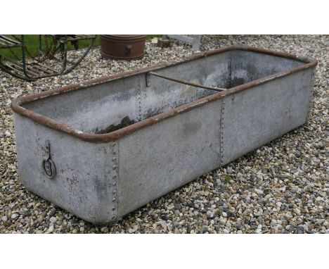 A large galvanised trough of riveted form, 182cm x 63cm x 41cm