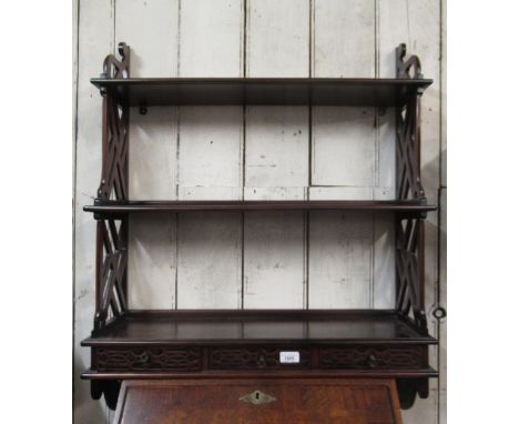 Reproduction mahogany Chippendale style three shelf wall bracket with three blind fretwork decorated drawers, 71cm wide 