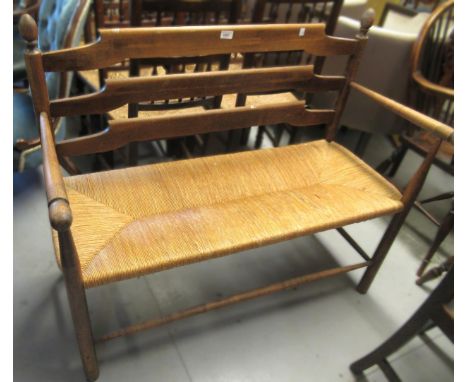 20th Century beechwood rail back bench, with rush seats on turned supports with stretchersLoose joints, seat is worn and need