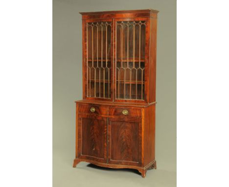 A 1920's figured mahogany serpentine fronted break-fronted bookcase, the upper part fitted two adjustable shelves enclosed by