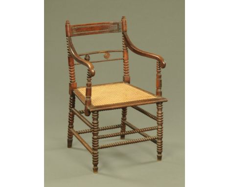 An early 19th century colonial Indian rosewood armchair, with bobbin ornament, scrolled arms and caned seats, 82 cm high.