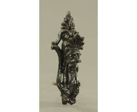 A Victorian black painted cast iron door knocker, modelled with a face mask and leaves.  25 cm high.  Indistinctly marked KEN