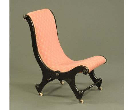 A late Victorian aesthetic movement ebonised nursing chair, upholstered in pink patterned fabric and raised on ceramic castor