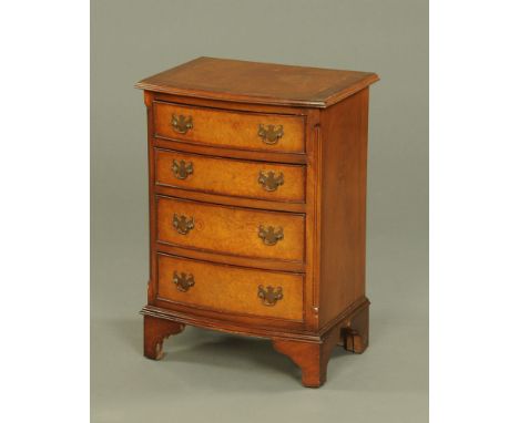 A reproduction walnut bow fronted chest of drawers, four long drawers with brass drop handles and all raised on bracket feet.