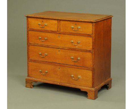 A late 18th century oak chest of drawers, with moulded edge above two short and three long graduated drawers with brass drop 
