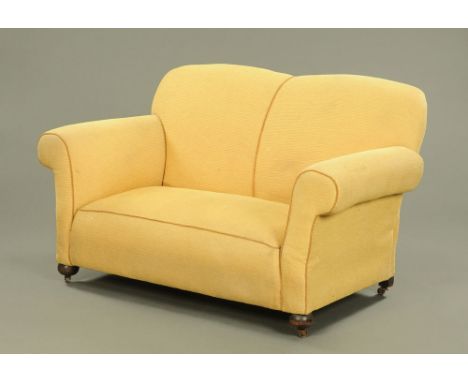 An Edwardian drop end two seat settee, upholstered in yellow cloth on turned front legs and castors.  145 cm wide.