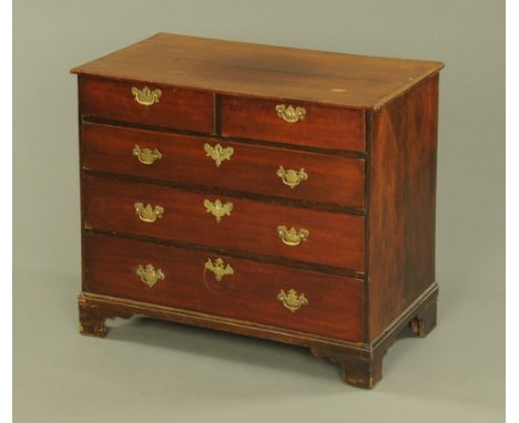 A George III oak chest of drawers, the top with angled moulding, fitted two short and three long drawers with later escutcheo