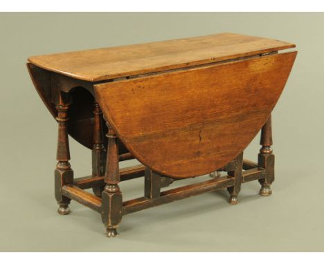 An 18th century oak gate legged dining table, oval in plan with turned legs and moulded stretchers and raised on short feet. 