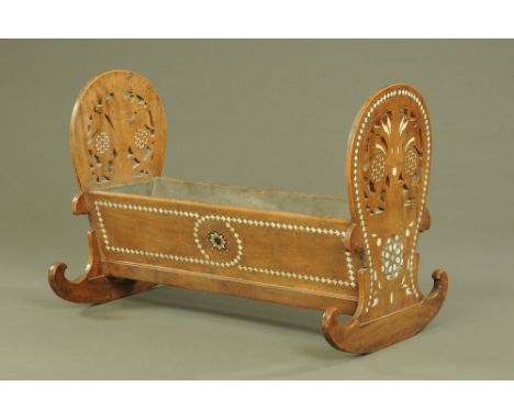 An early 20th century near Eastern mahogany rocking crib, with shaped and pierced ends, inlaid in bone, mother of pearl and w