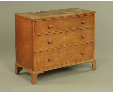An early 19th century oak chest of drawers, with moulded edge above three long graduated drawers with wooden knob handles and