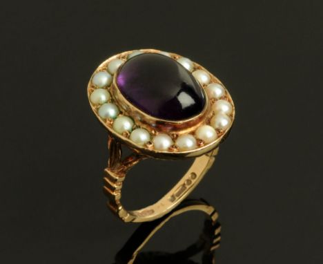 A 9 ct gold ring set with an amethyst coloured cabochon and seed pearl surround. Size M, 8.6 grams.