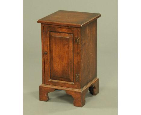 A reproduction oak bedside cabinet, with moulded edge, single panelled door and raised on bracket feet.  Height 59 cm, width 