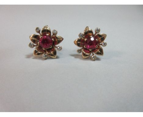A pair of synthetic ruby and diamond flower earstuds, each with a 6mm round cut ruby claw set at the centre of five curved pe