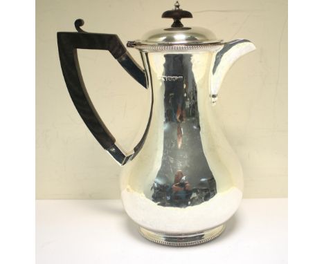 A silver hotwater jug, by Lee & Wigful, Sheffield 1914, of plain baluster form with beaded edge and foot, ebonised handle and