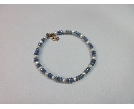 A sapphire bead and pearl bangle, with trios of faceted sapphire beads spaced by 3.5mm pearls on a wire hoop, to a trigger cl