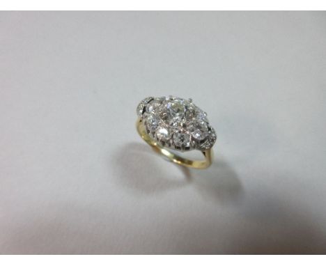 An unusual diamond cluster ring set in 18ct gold, designed as a horizontal oval flowerhead with a principal old round brillia