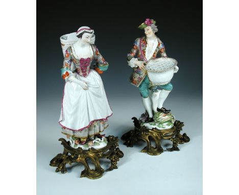 A pair of Meissen figures of gardeners, he wearing a green hat, floral decorated coat, green britches, holding a pannier, his