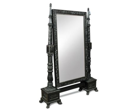 An early 19th century Anglo-Indian carved ebony cheval glass, the rectangular plate supported by turned and carved columns, e