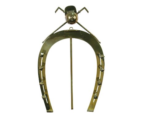 An early 20th century easel back horseshoe-shaped brass hunting whip rack, the horseshoe with four hanging pegs to either sid