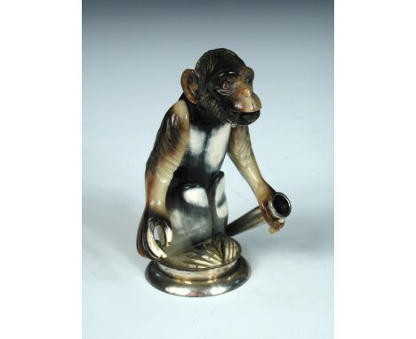 An Austrian novelty silver mounted monkey figure, maker MG, Vienna 1867-1922, carved from horn he is standing upright, a ciga