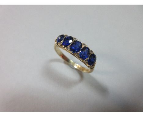 An Edwardian five stone sapphire ring with diamond highlights, the slightly graduated oval cut sapphires with eight rose cut 