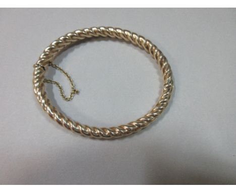 A barleysugar twist hinged bangle, the 5-6mm diameter twist of hollow structure in unmarked yellow precious metal, tests for 