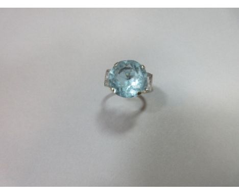 A colour change blue paste ring, the large round cut stone, 14mm diameter, four claw set between baguette cut white stone sho