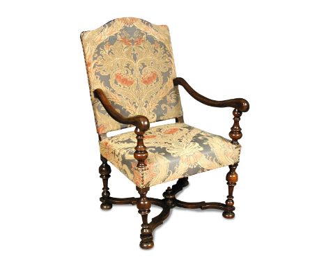 A 17th century walnut armchair, with an arched back, upholstered in a woven tapestry patterned fabric, on turned legs joined 
