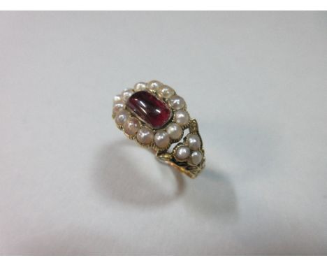 A Georgian ruby and pearl ring dated 1792, set to the centre with a rectangular cushion cabochon ruby in a border of half pea