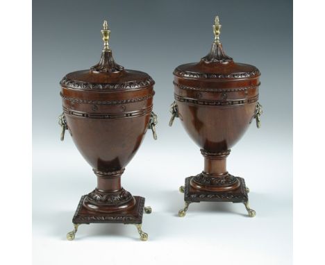 A pair of George III style carved mahogany and brass chestnut urns, with brass finial over foliate-carved lid fitting on urn 